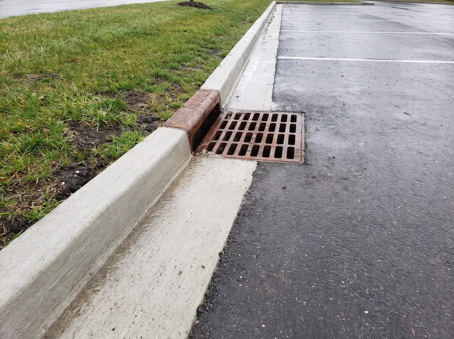 Cast-in-place concrete curb and gutter directing water to a catch basin in a commercial lot