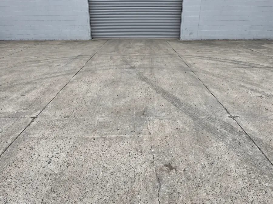 Reinforced concrete loading apron with saw-cut control joints at a commercial overhead door
