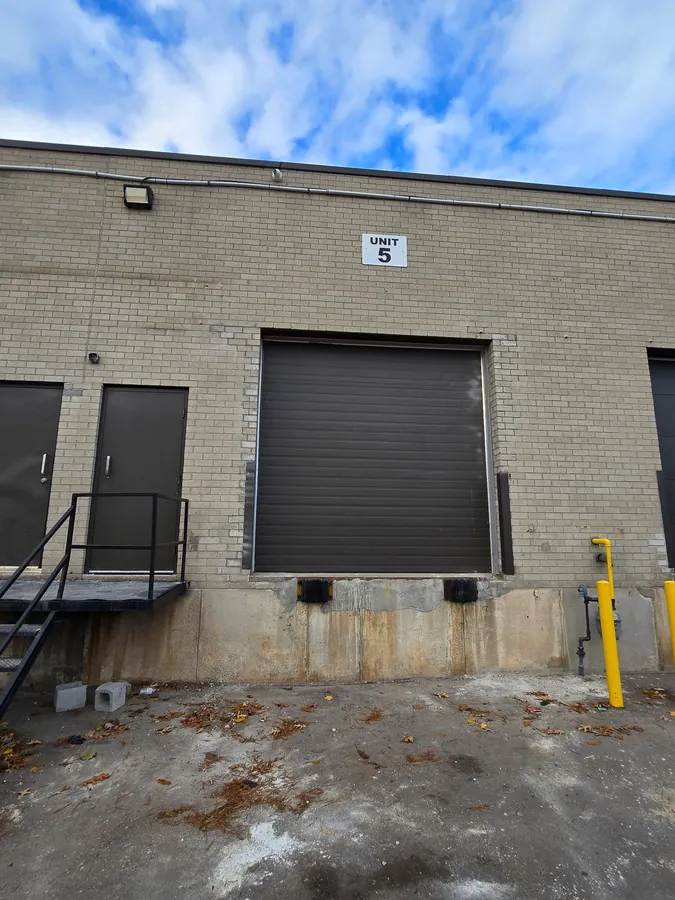 Black rubber dock bumpers and steel jamb guards protecting a warehouse loading dock door