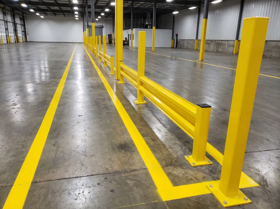 Painted pedestrian walkway separated from a forklift aisle by yellow barrier posts