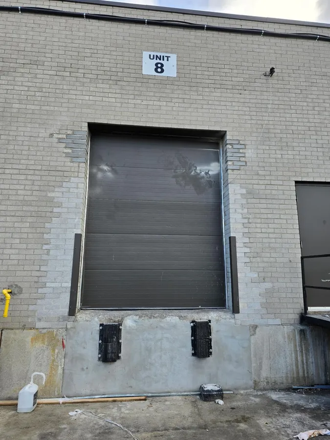 Industrial loading dock with newly resurfaced concrete dock wall, steel bumpers and rebuilt brick surround.