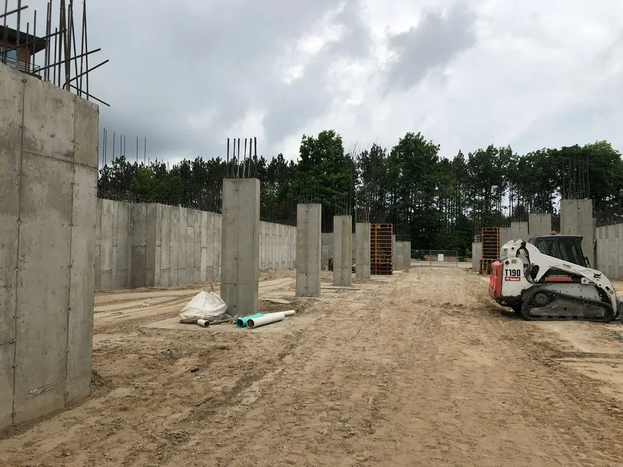 Poured reinforced concrete foundation walls and columns with exposed rebar on a graded construction site