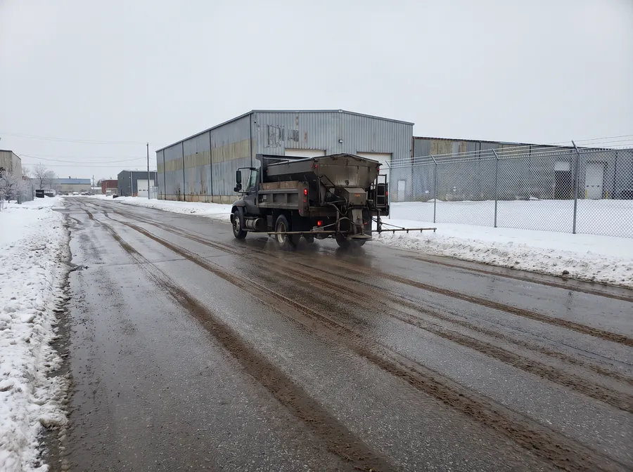 Brine applicator truck laying anti-icing treatment along an industrial roadway