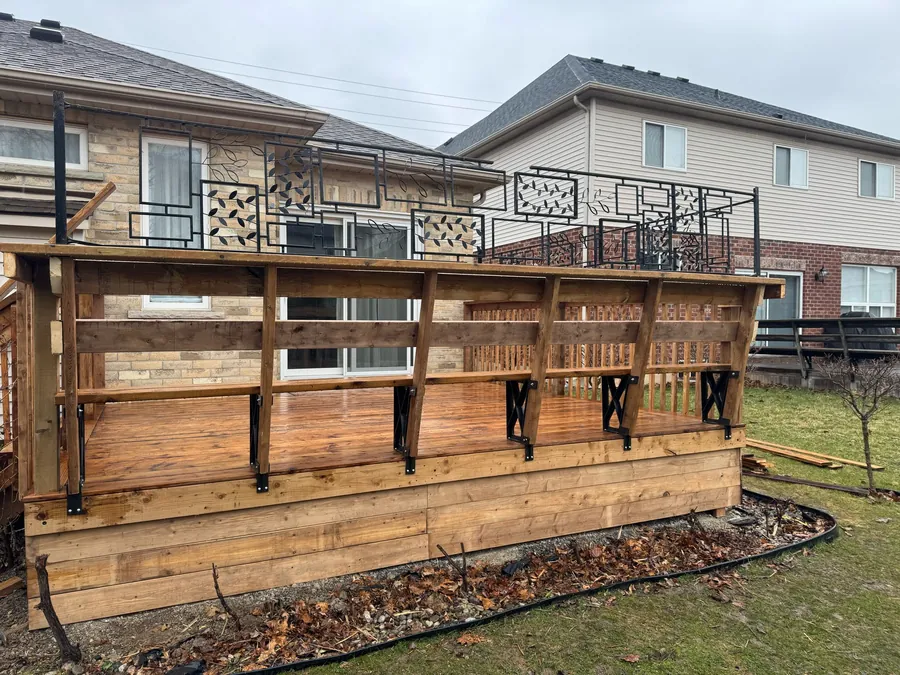 Warm reddish-brown natural wood deck boards with visible knots and grain, wood privacy screen, evening light.
