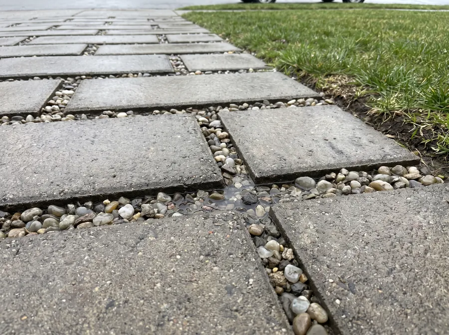 Permeable paver driveway with aggregate-filled joints draining rainwater on site
