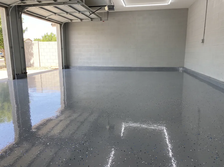 Glossy grey epoxy garage floor with decorative flake and a clean coved wall edge